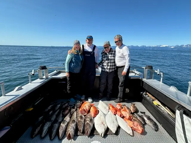 Rockfish and silver salmon on a boat deck below mountains
