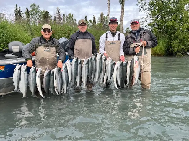 Four anglers standing in the Kenai River holding a string of sockeye salmon