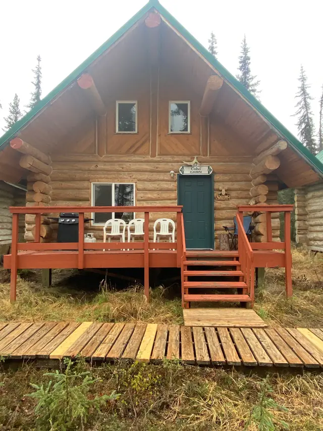 A log cabin with a red deck and a boardwalk